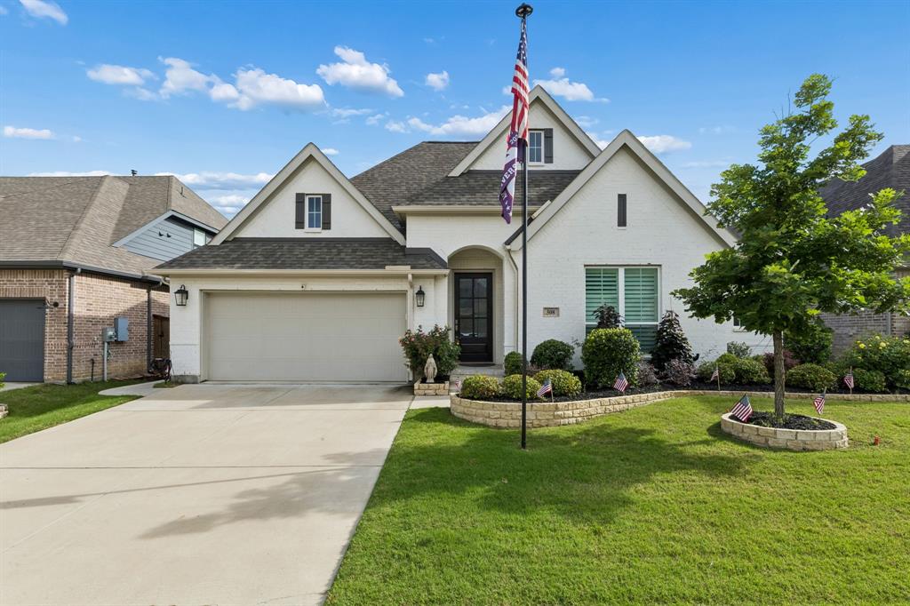 Brick exterior featuring multiple gables, a covered entryway, concrete driveway, and stone-bordered landscaping Brick exterior featuring multiple gables, a covered entryway, concrete driveway, and stone-bordered landscaping