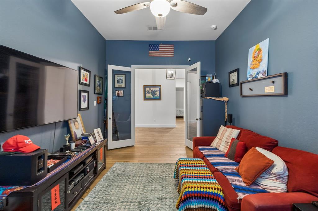 High ceilings featuring a central light fixture with a ceiling fan, complemented by wood-finish flooring and double glass-panel doors