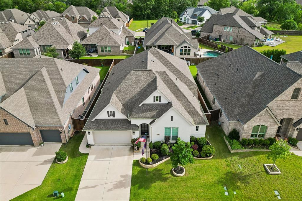 White masonry exterior featuring a multi-gabled roof, two-car garage, and manicured front lawn with established shrubbery White masonry exterior featuring a multi-gabled roof, two-car garage, and manicured front lawn with established shrubbery
