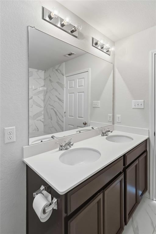 Dual-sink vanity with white composite countertop, dark cabinetry, large wall-mounted mirror, and multi-light fixtures