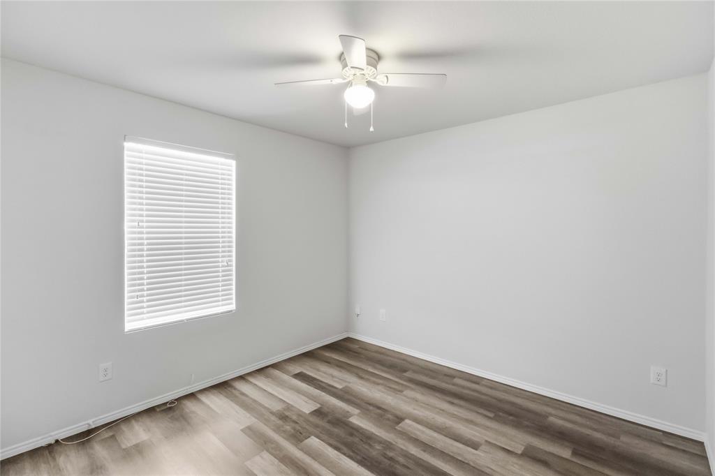 Room featuring wood-finish flooring, a neutral color palette, a window with horizontal blinds, and a ceiling-mounted light fixture with fan blades