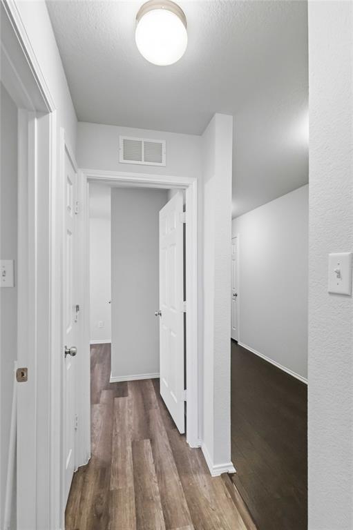 Interior hallway featuring wood-finish flooring, crisp neutral wall paint, and traditional white six-panel doors
