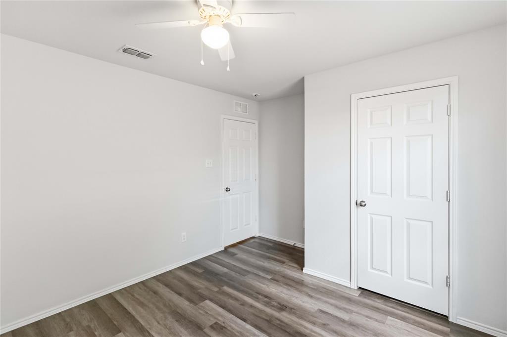 Interior room featuring wood-finish flooring, neutral wall paint, and a ceiling-mounted light fixture with an integrated fan
