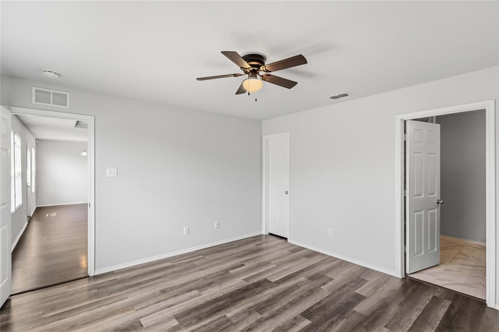 Neutral-toned interior featuring wood-finish flooring, a ceiling fan with integrated lighting, and six-panel interior doors