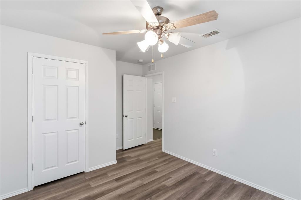Interior space featuring wood-finish flooring, a multi-light ceiling fan with neutral-finish blades, and white six-panel interior doors