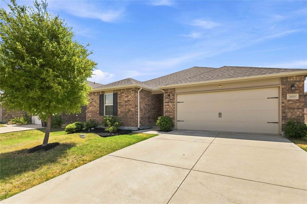 Single-story brick exterior featuring a hip roof, multi-panel garage door, and a concrete driveway