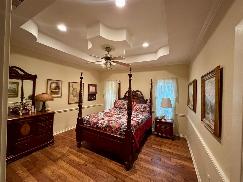 Tray ceiling with recessed lighting, wood-finish flooring, and chair rail molding