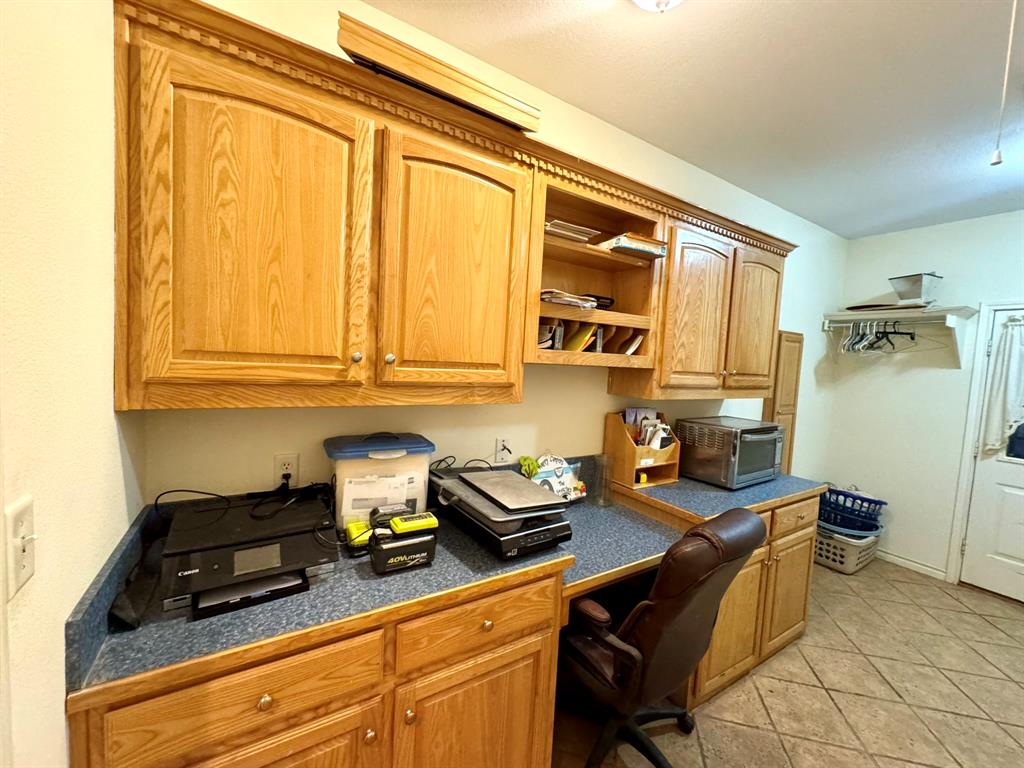 Custom cabinetry with crown molding, integrated open shelving, solid-surface countertops, and ceramic tile flooring