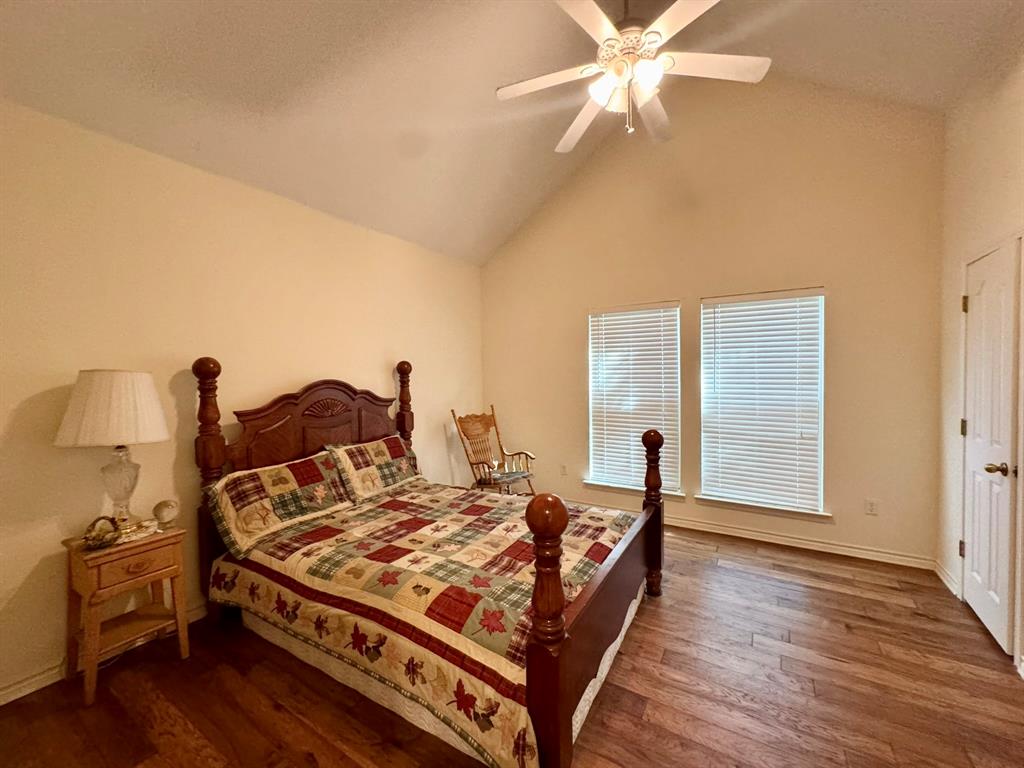 Vaulted ceilings, wood-finish flooring, dual windows with integrated blinds, and a multi-light ceiling fan