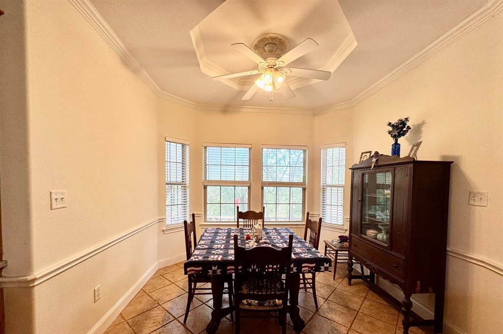 Octagonal tray ceiling, tile flooring, crown molding, chair rail trim, and a multi-light ceiling fan