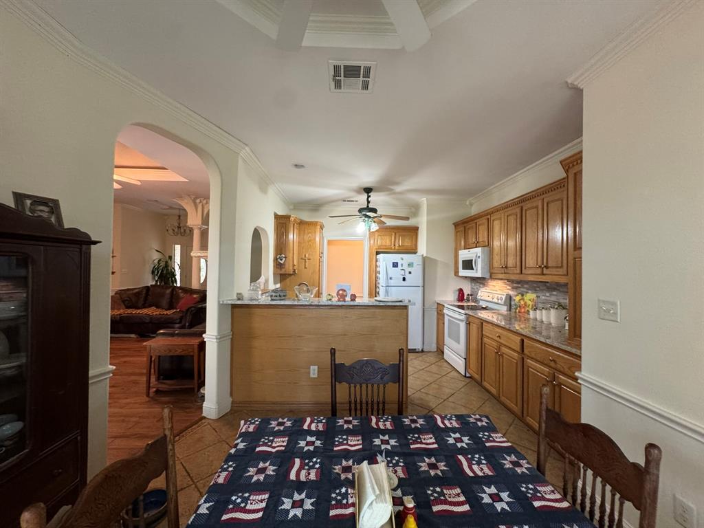 Kitchen featuring wood cabinetry, stone-finish countertops, tile flooring, and a breakfast bar with built-in millwork