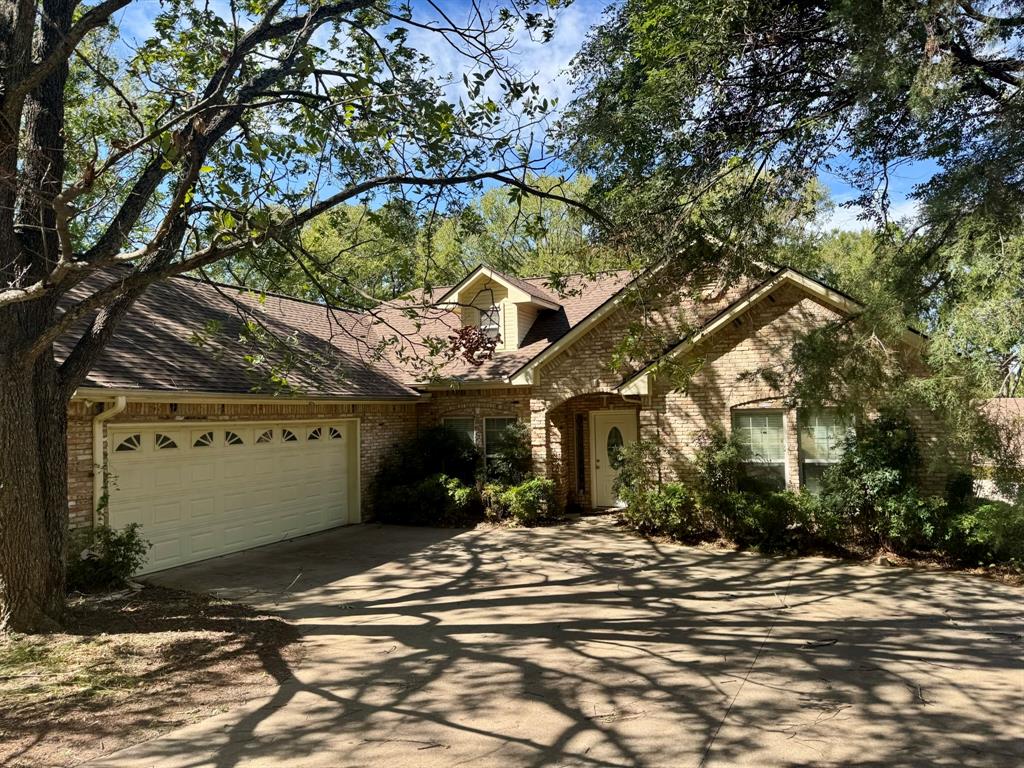 Brick exterior featuring a gabled roofline, arched entryway, multi-paned windows, and an attached two-car garage Brick exterior featuring a gabled roofline, arched entryway, multi-paned windows, and an attached two-car garage
