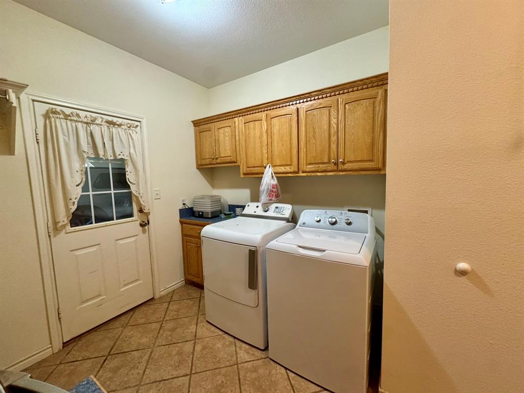 Utility area featuring wood-finish cabinetry, tile flooring, and exterior access door
