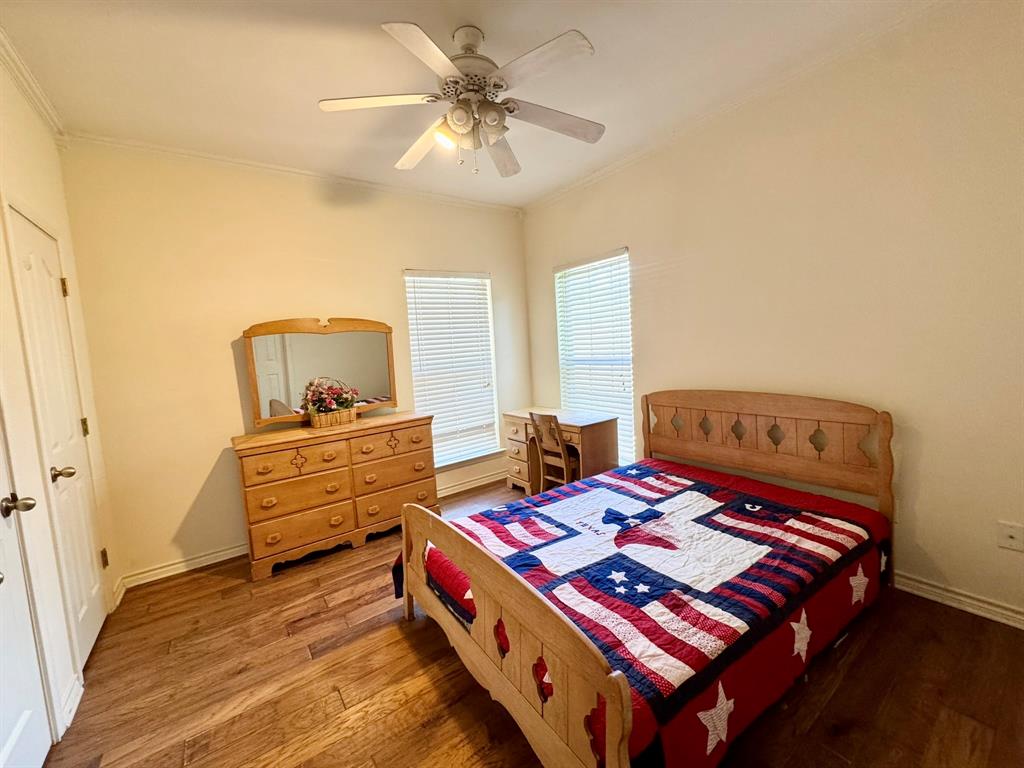 Wood-finish flooring, ceiling fan with integrated lighting, and dual windows with horizontal blinds