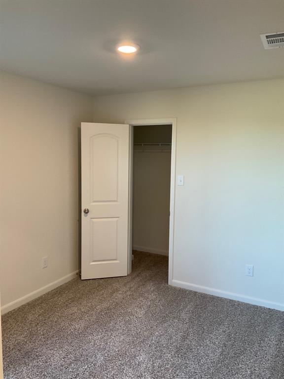 Neutral-toned carpeting, recessed ceiling lighting, and a two-panel interior door opening to a closet with built-in wire shelving