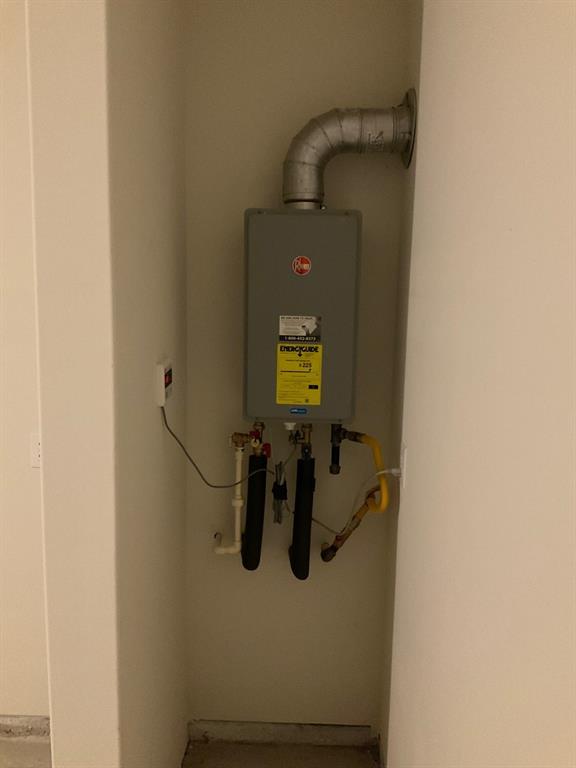 Wall-mounted tankless water heater featuring metal venting, insulated piping, and integrated electronic control panel