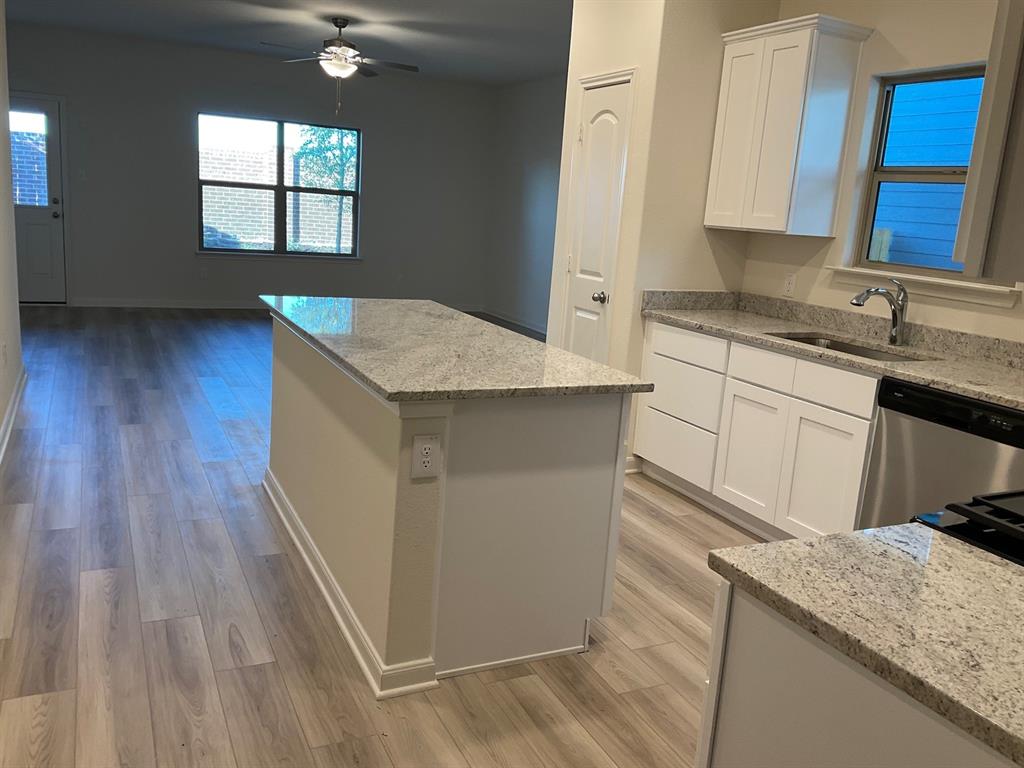 Kitchen featuring white cabinetry, stone-finish countertops, a central island, and wood-finish flooring