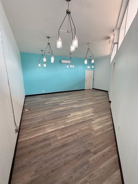 Interior room featuring wood-finish flooring, vaulted ceilings with clerestory windows, and four multi-light metal chandeliers