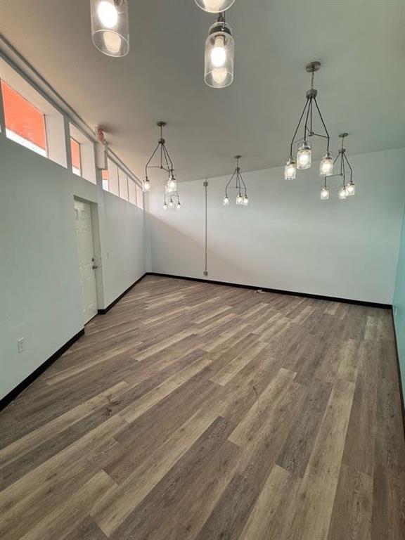 Interior space featuring wood-finish flooring, clerestory windows, and multiple multi-light pendant fixtures with glass shades