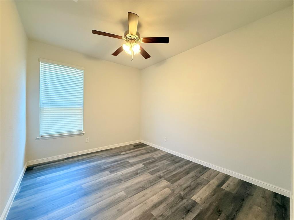 Room featuring wood-finish flooring, a neutral color palette, and an attached multi-blade ceiling fan with integrated lighting