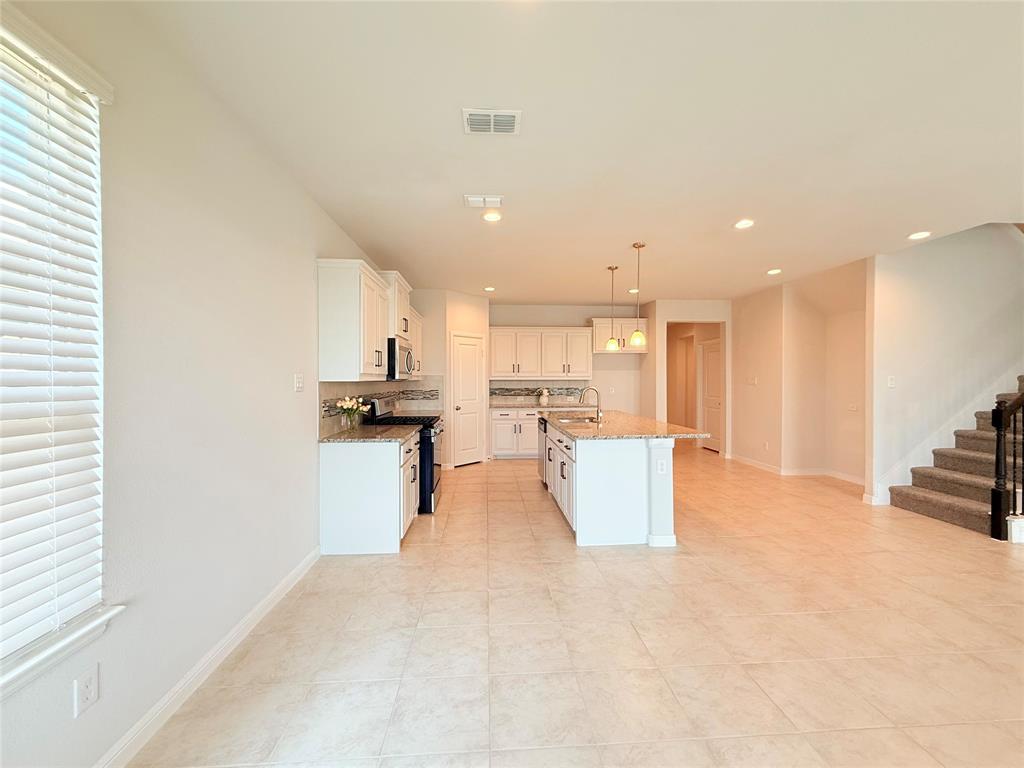 Kitchen featuring white cabinetry, stone-surface countertops, central island, tile flooring, and pendant lighting