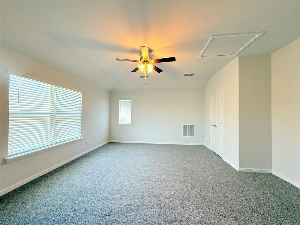 Neutral interior space featuring wall-to-wall carpeting, multiple windows with horizontal blinds, and a ceiling fan with integrated lighting