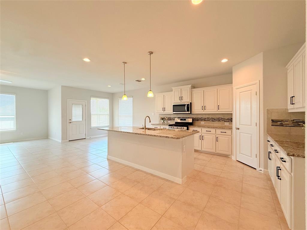 Kitchen featuring a stone-surface island, white cabinetry, decorative tile backsplash, recessed lighting, and pendant fixtures