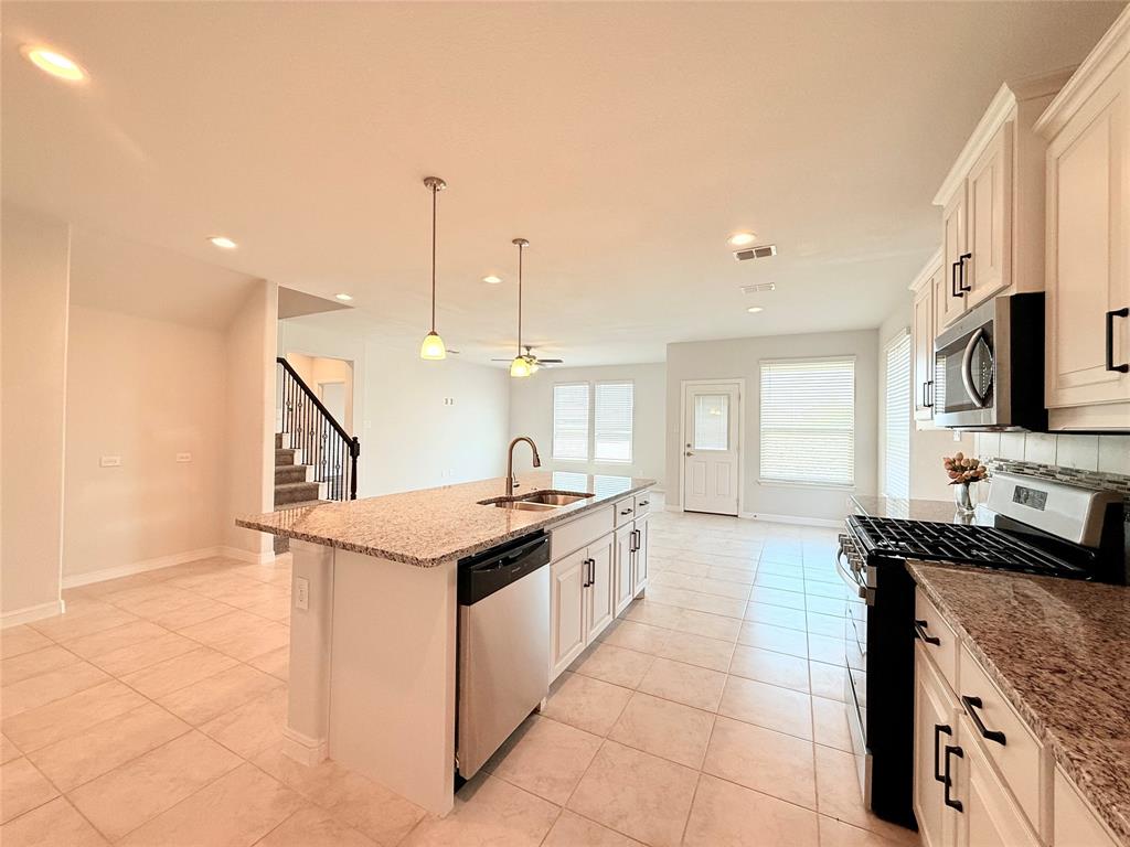 Kitchen featuring a center island, stone-finish countertops, tile flooring, white cabinetry with dark hardware, and recessed lighting