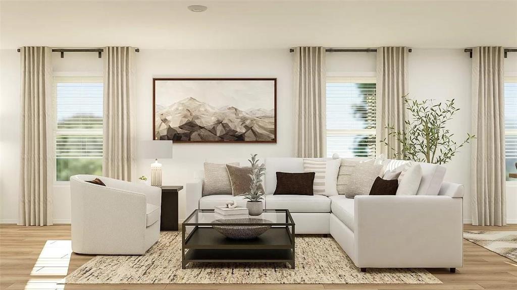 Living area featuring wood-finish flooring, three oversized windows, and neutral wall tones Living area featuring wood-finish flooring, three oversized windows, and neutral wall tones