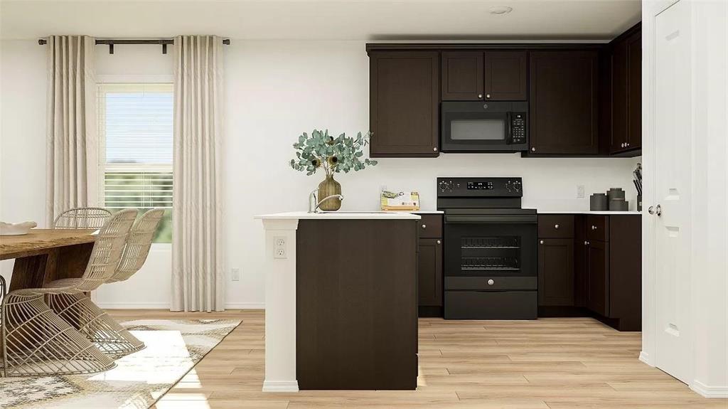 Kitchen featuring dark cabinetry, matching black appliances, central island, and wood-finish flooring Kitchen featuring dark cabinetry, matching black appliances, central island, and wood-finish flooring