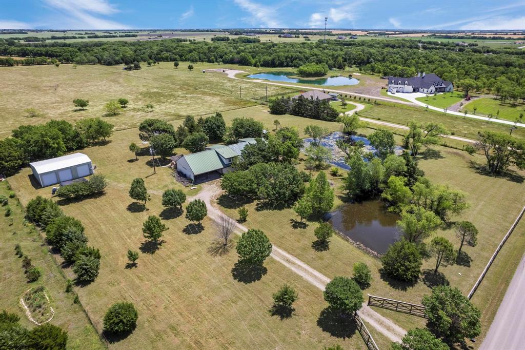 Expansive acreage featuring multiple ponds, mature trees, a detached workshop, and a gravel driveway