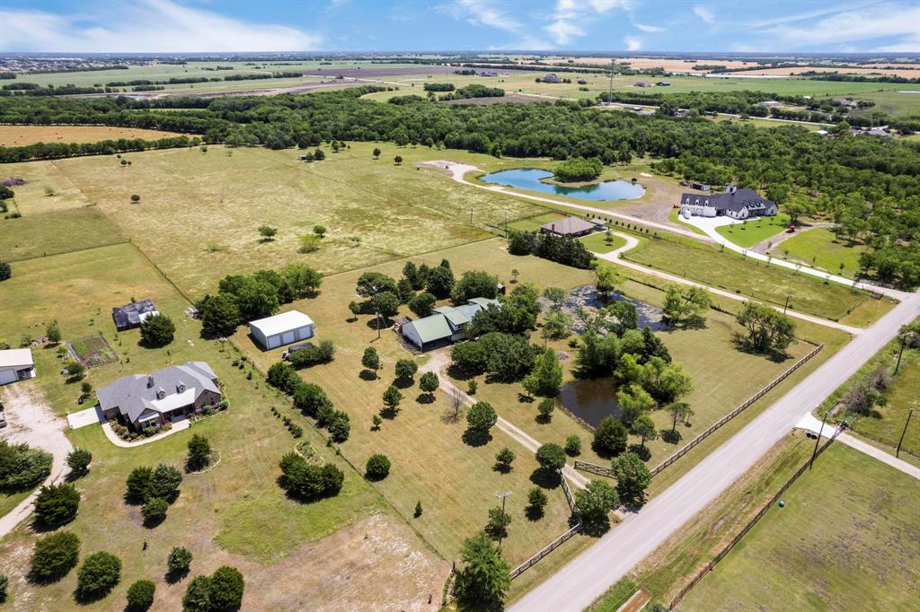 Expansive acreage featuring mature trees, multiple ponds, perimeter fencing, and detached workshop structures