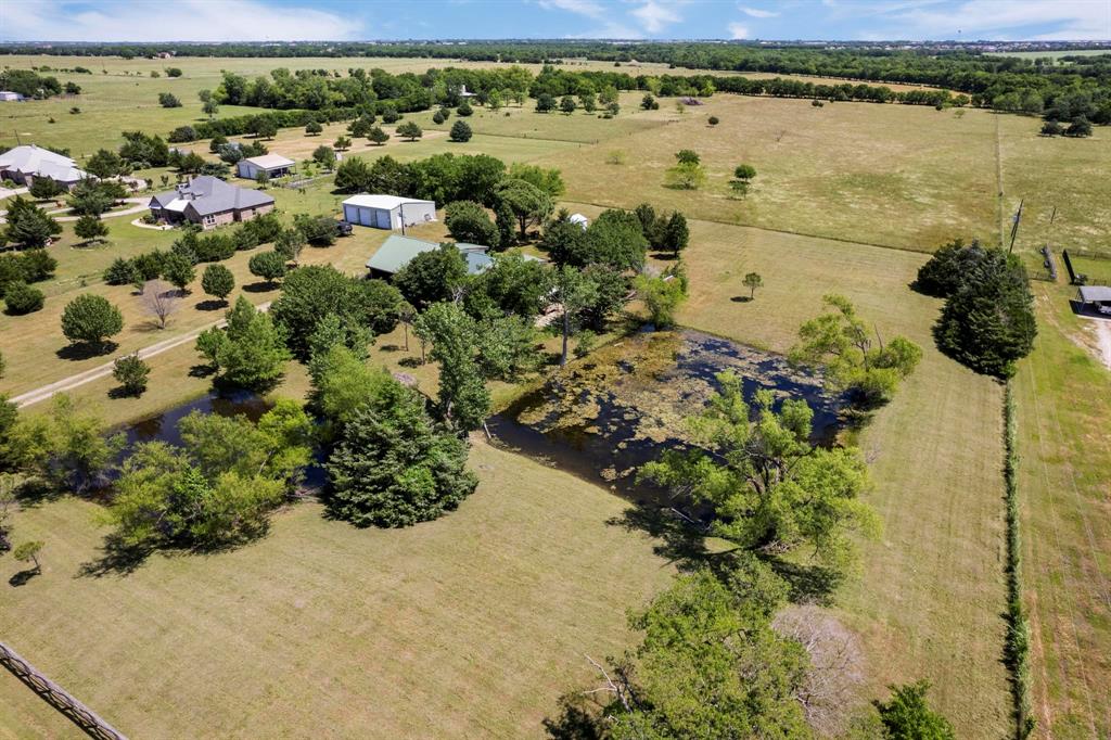 Expansive acreage featuring mature trees, two bodies of water, and a detached metal-sided outbuilding