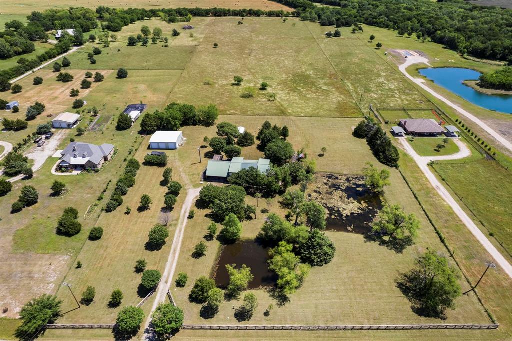 Expansive acreage featuring multiple fenced paddocks, two distinct ponds, mature tree clusters, and a large detached metal workshop