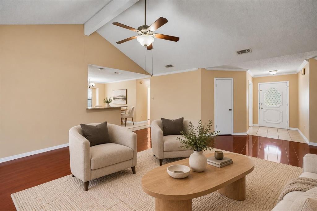 Vaulted ceilings, wood-finish flooring, ceiling fan with integrated lighting, pass-through opening, and a paneled entry door with decorative glass inlay Vaulted ceilings, wood-finish flooring, ceiling fan with integrated lighting, pass-through opening, and a paneled entry door with decorative glass inlay