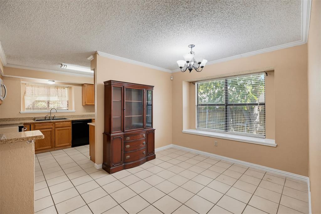 Kitchen featuring tile flooring, stone-surfaced countertops, wood cabinetry, built-in multi-arm light fixture, and large window with built-in sill