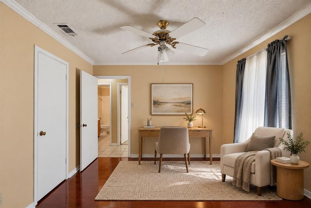 Wood-finish flooring, ceiling fan with integrated lighting, crown molding, and neutral wall tones