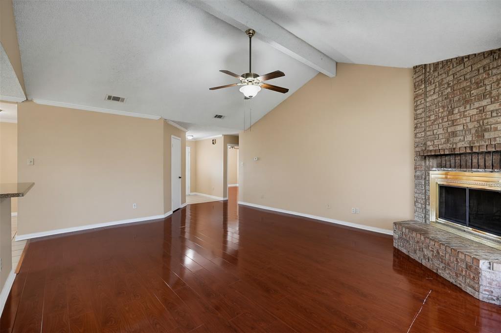Vaulted ceiling with exposed beam, wood-finish flooring, and brick fireplace with a metallic finish surround Vaulted ceiling with exposed beam, wood-finish flooring, and brick fireplace with a metallic finish surround