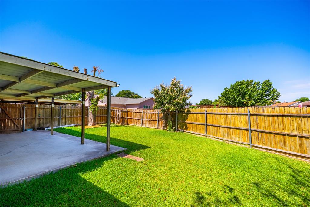 Backyard featuring a concrete-floored covered patio, wood privacy fencing, and a grass lawn