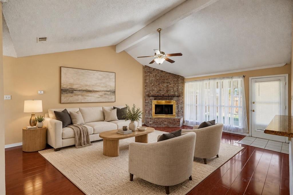 Vaulted ceiling with exposed beam, corner masonry fireplace with hearth, and dark wood-finish flooring Vaulted ceiling with exposed beam, corner masonry fireplace with hearth, and dark wood-finish flooring