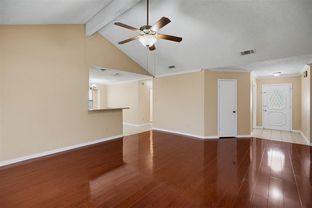 Vaulted ceilings, wood-finish flooring, ceiling fan with integrated lighting, pass-through opening, and decorative glass-panel entry door Vaulted ceilings, wood-finish flooring, ceiling fan with integrated lighting, pass-through opening, and decorative glass-panel entry door