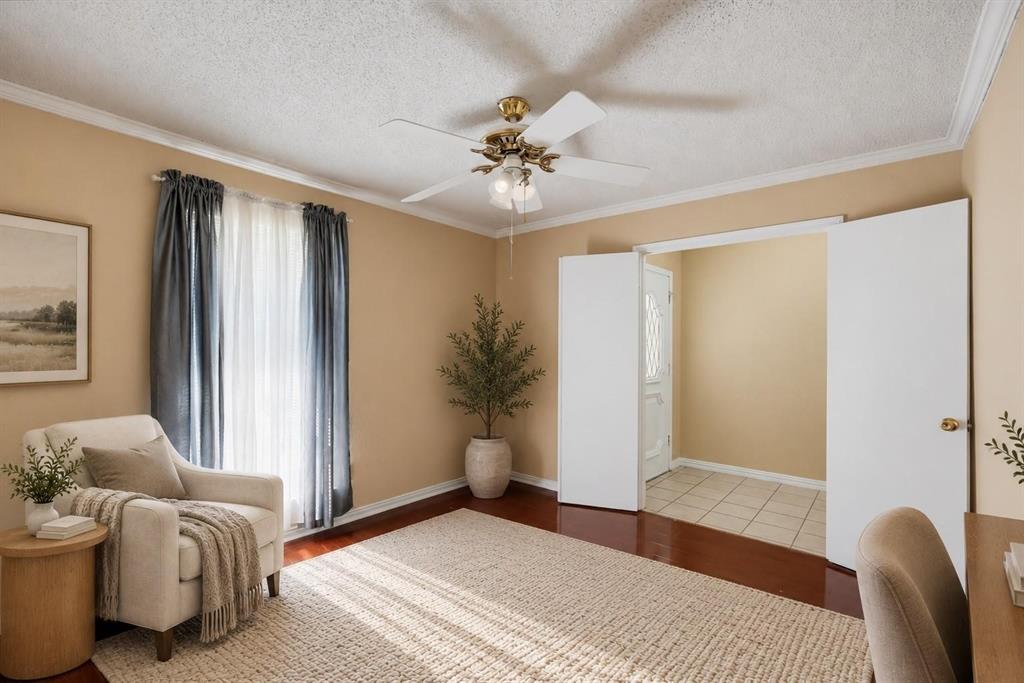 Interior space featuring wood-finish flooring, ceiling fan with integrated lighting, textured ceiling, and crown molding