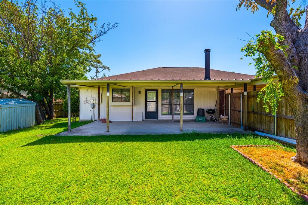 Backyard featuring a concrete patio, covered porch area, wood fencing, and mature trees