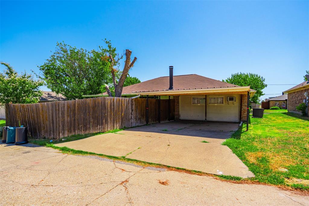 Exterior featuring a concrete driveway, covered carport, and wood privacy fencing