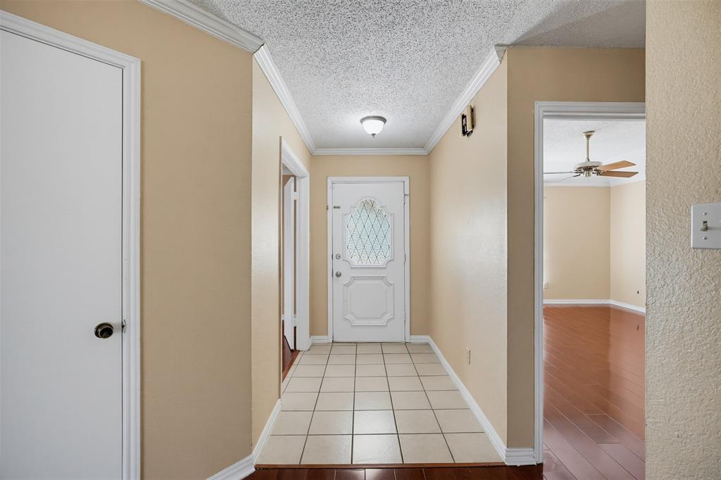 Entryway featuring a white front door with decorative leaded glass, ceramic tile flooring, and crown molding Entryway featuring a white front door with decorative leaded glass, ceramic tile flooring, and crown molding