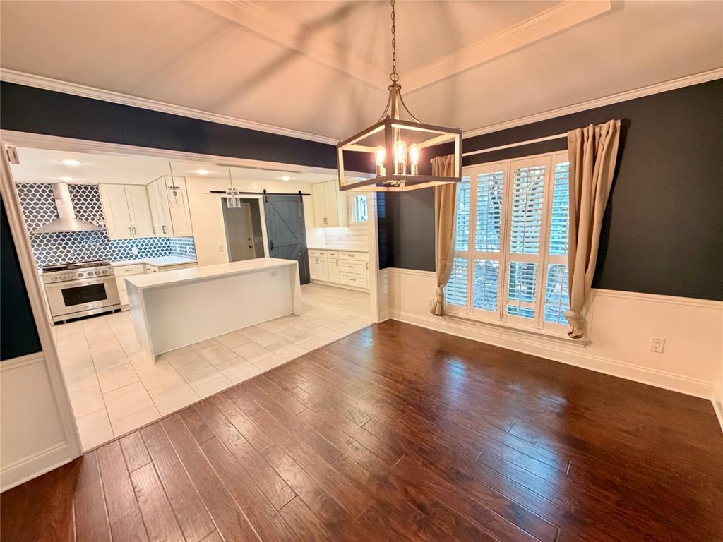 Dining area featuring tray ceiling, wood-finish flooring, and white wainscoting