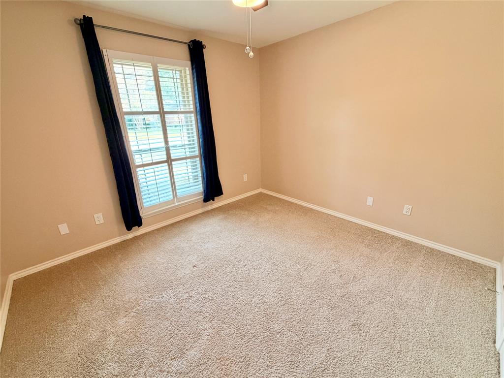 Neutral carpeting, window with louvered shutters, and ceiling-mounted light fixture