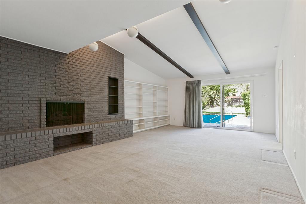 Sizable living area with striking floor-to-ceiling brick fireplace and built-in shelving.