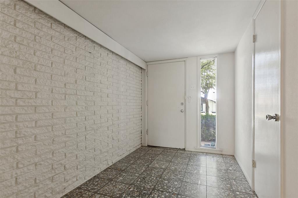 Distinctive entry foyer with a textured brick accent wall and terrazzo flooring