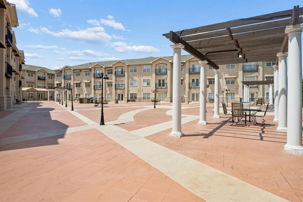 Expansive paved courtyard featuring multiple pergolas, outdoor seating, and integrated lighting fixtures